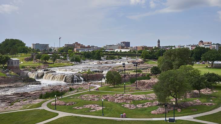A series of falls in the middle of an urban park surrounded by greenery