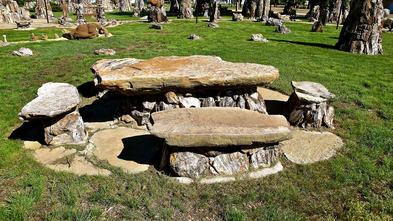Table and benches made of rocks on a grassy lawn filled with various rock formations