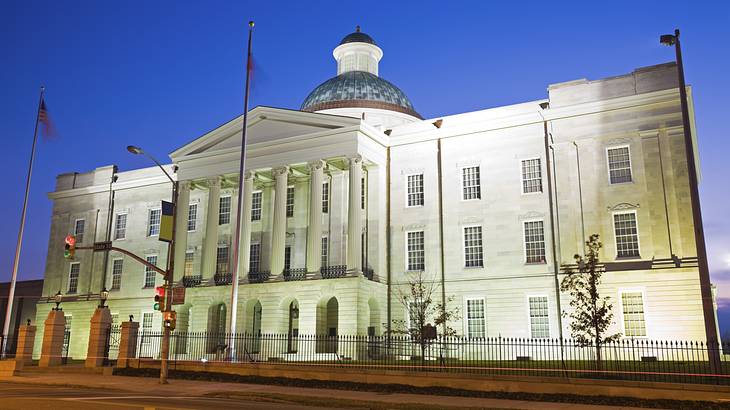 An illuminated building made of limestone, brick, and cement with flags in front An illuminated building made of limestone, brick, and cement with flags in front