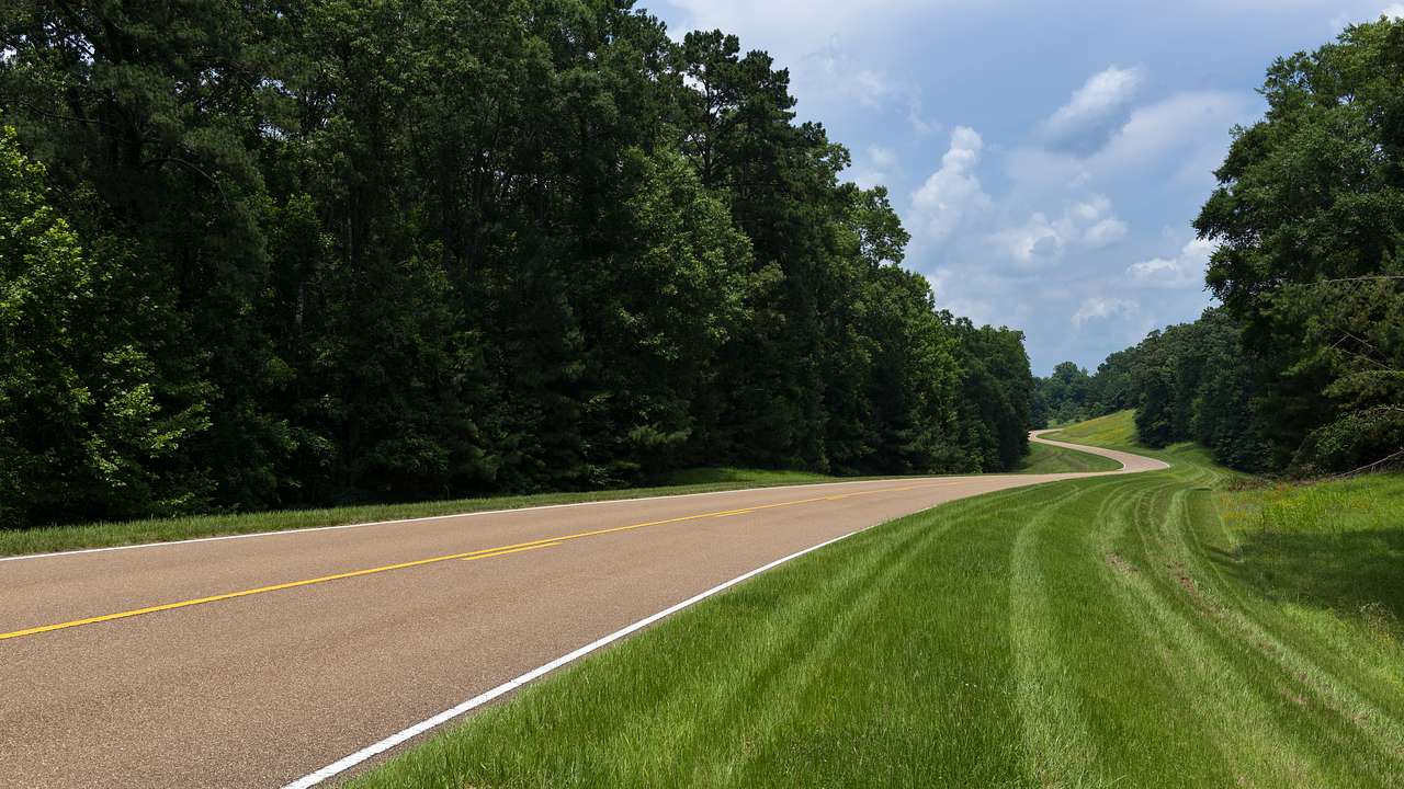 A long winding road with grass and trees on either side