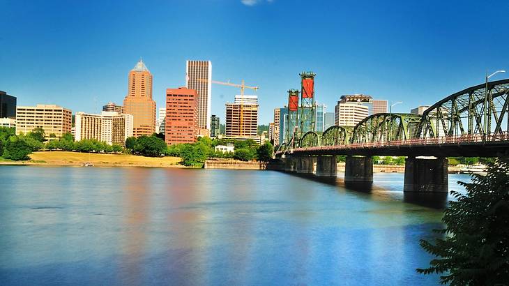 A river with a bridge over it and city buildings on the shore on a clear day