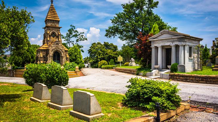 Tombstones, graves, and mausoleums in a manicured cemetery on a sunny day