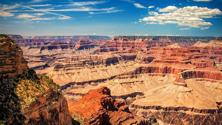 A view of part of the Grand Canyon with red rock cliffs under a blue sky with clouds