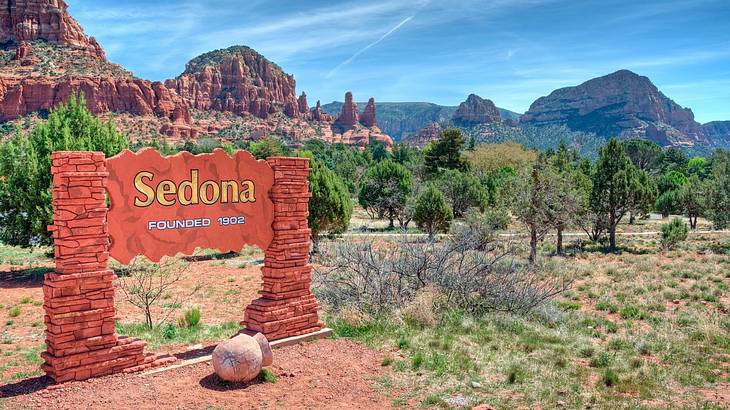 A sign that says "Sedona founded 1902" with trees and red rock cliffs behind it A sign that says "Sedona founded 1902" with trees and red rock cliffs behind it