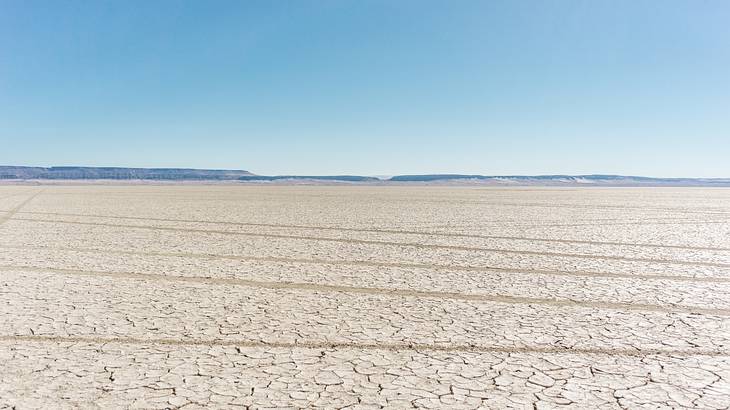 Cracked soil of a plain with mountains and a clear sky in the distance Cracked soil of a plain with mountains and a clear sky in the distance