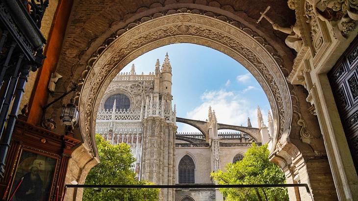 A view of a cathedral, trees, and a blue sky through a rounded arch