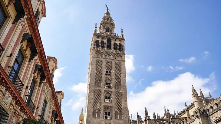 A tall tower with an intricate design and a pointy top, with buildings and sky around