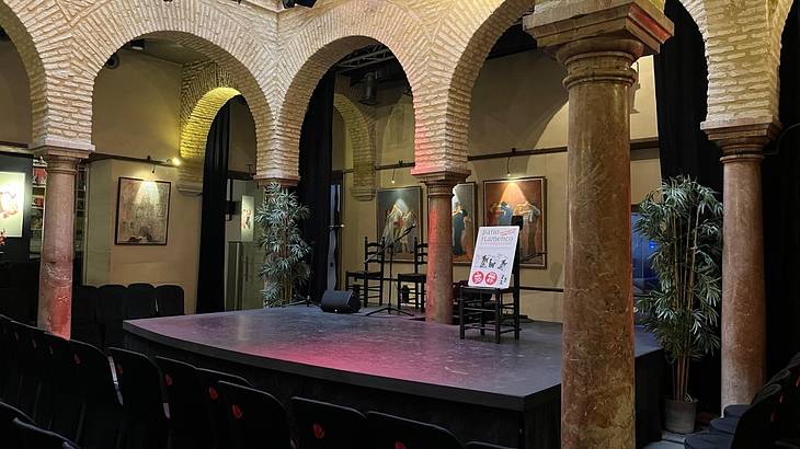 A stage with chairs in front of it in a room with stone arches