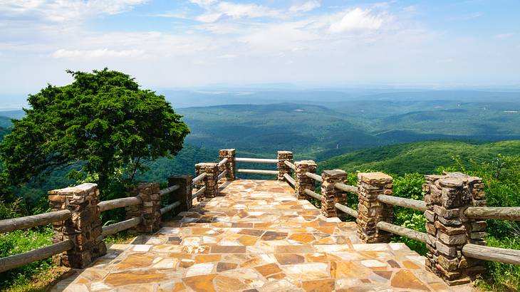 A viewing deck on top of a mountain overlooking a green valley below