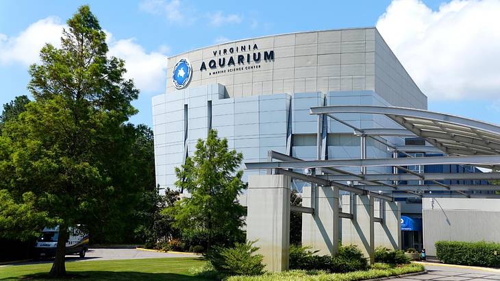 A large building with a Virginia Aquarium sign and grass and trees in front of it