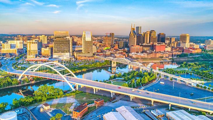 An aerial view of a city with bridges over a river, trees, and buildings at sunset An aerial view of a city with bridges over a river, trees, and buildings at sunset