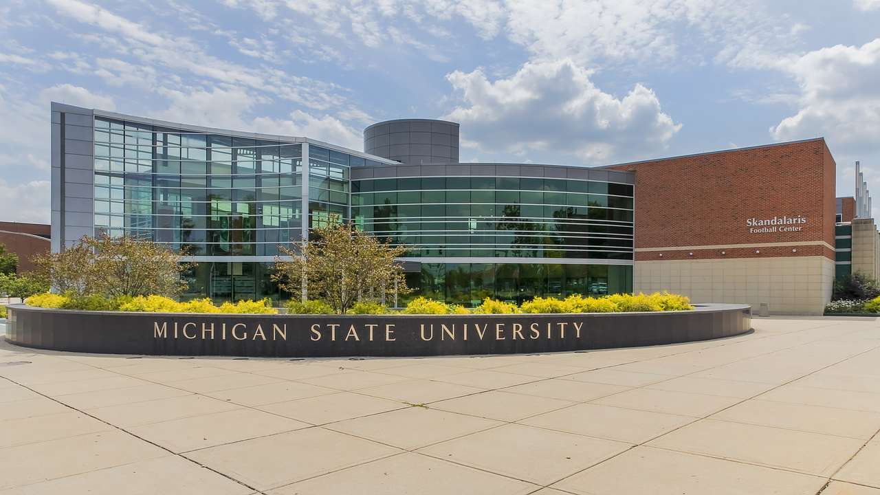 A building with glass walls and a plant box in front with Michigan State University