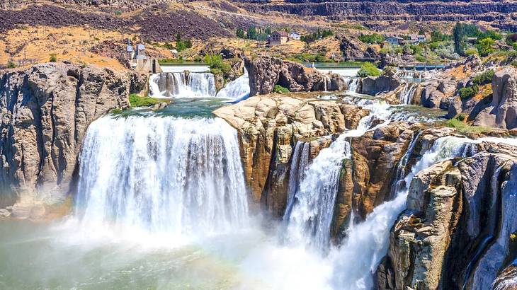 Aerial of a wide waterfall beside thinner cascading waterfalls from a rugged cliff Aerial of a wide waterfall beside thinner cascading waterfalls from a rugged cliff