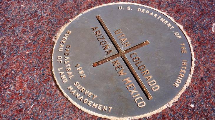 A round monument on the floor with text of Arizona, New Mexico, Utah, and Colorado