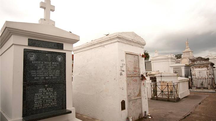 A cemetery with a white grave with a cross beside other white graves