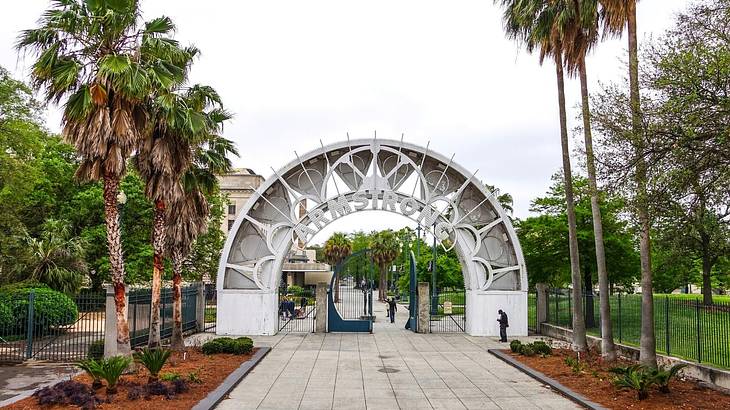An arched white gate with the text of "Armstrong," with palm trees on each side