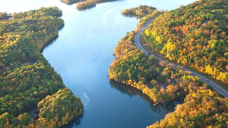 A river meandering across a green hill with a curving road A river meandering across a green hill with a curving road