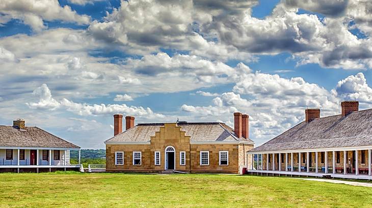 Looking at three vernacular houses on green grass under a partly cloudy sky Looking at three vernacular houses on green grass under a partly cloudy sky