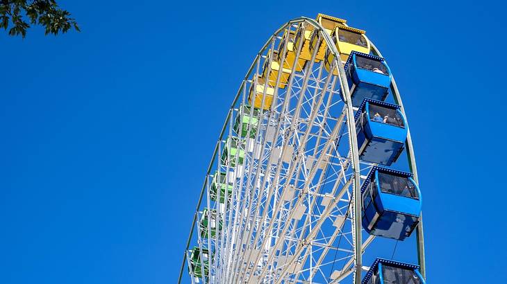 Looking up at a multi-color Ferris wheel against a clear blue sky
