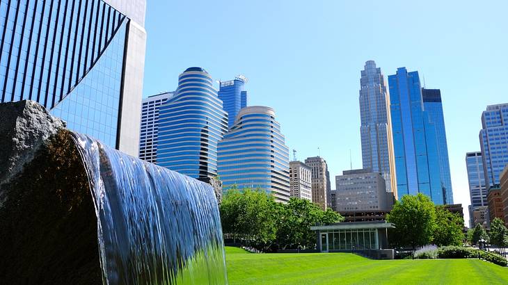 A fountain with water streaming downwards against modern tall buildings