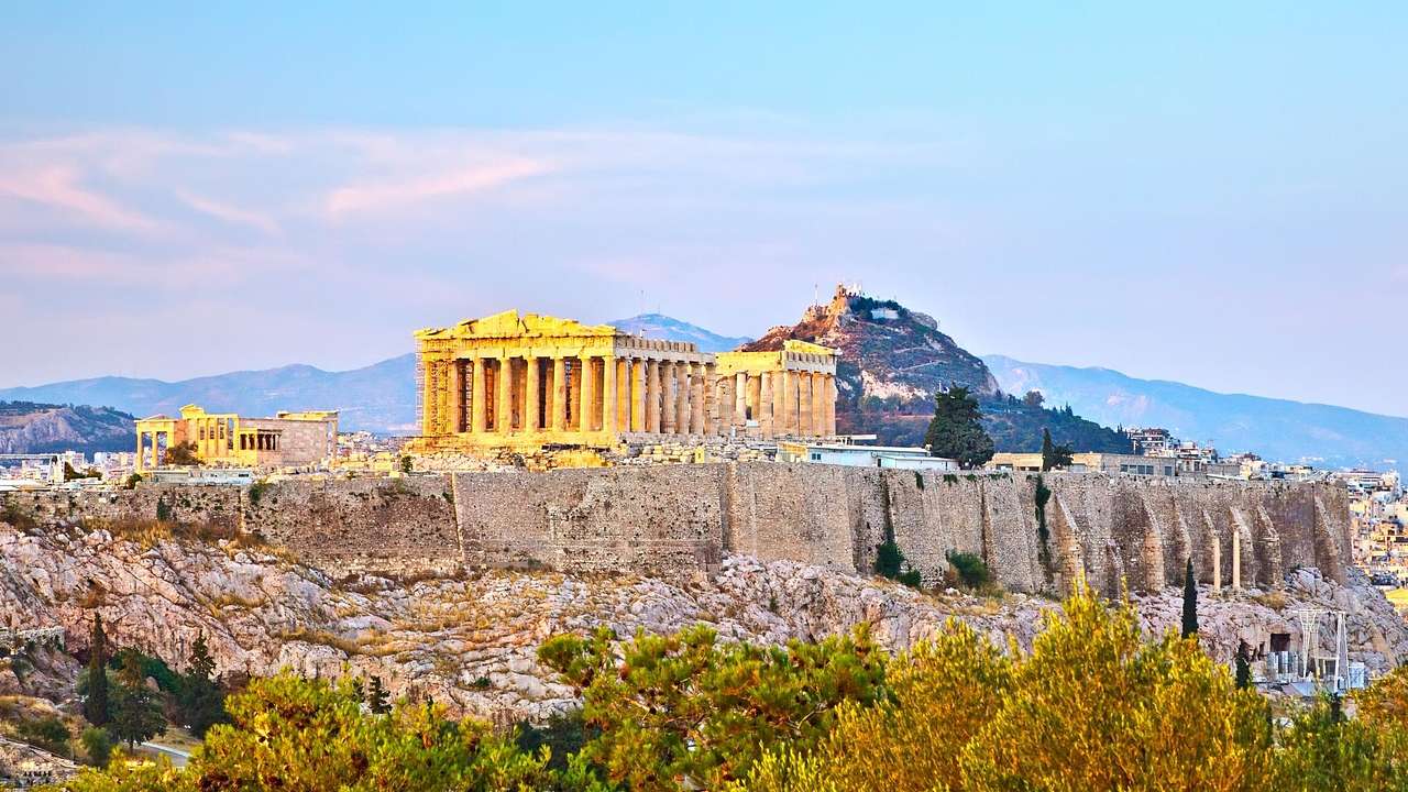 An ancient Greek structure with many columns under a pink-blue sky