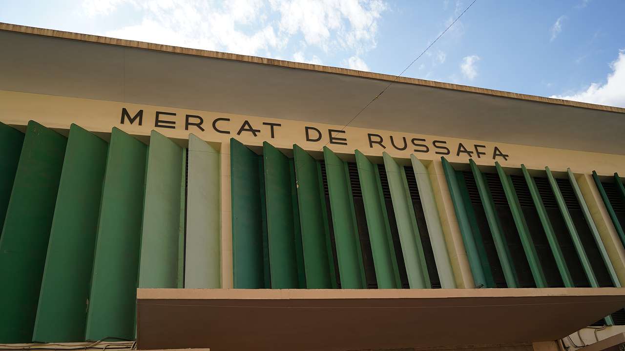 The entrance sign to Mercat de Russsafa with large vertical green ventilation grills