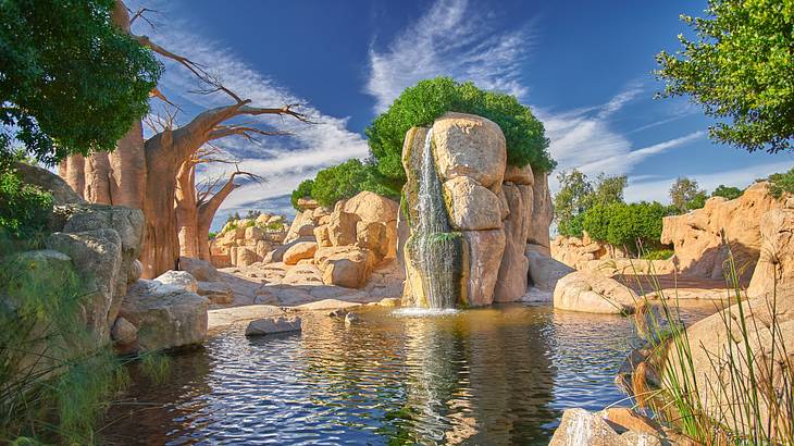A human-made lagoon with a small waterfall and boulders around