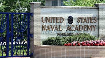 A brick wall and a gate with a "United States Naval Academy" sign