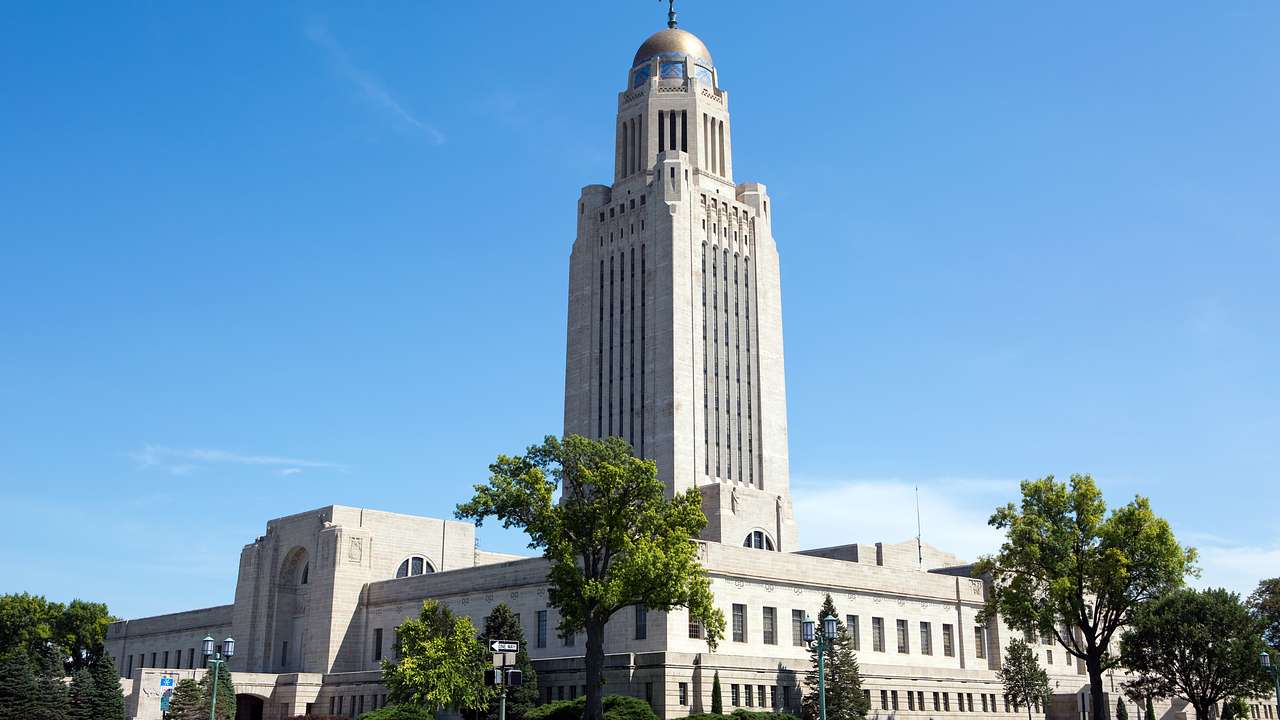 A white building with a dome tower surrounded by trees on a sunny day
