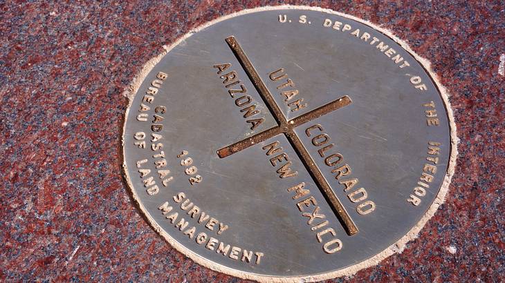 A round monument on floor with text of New Mexico, Arizona, Colorado, and Utah