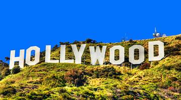 The Hollywood Sign sitting on a greenery-covered hill under a blue sky