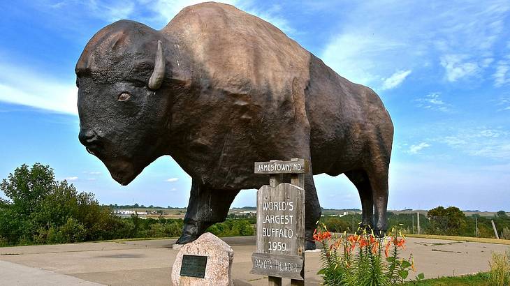A sign of "world's largest buffalo" against a sculpture of a buffalo A sign of "world's largest buffalo" against a sculpture of a buffalo