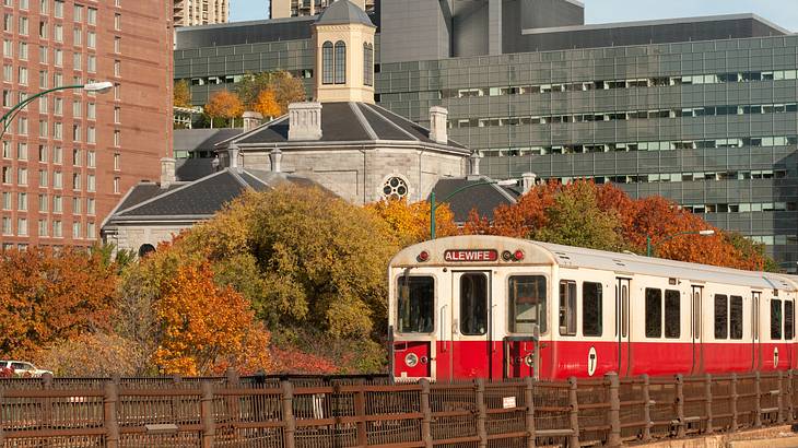 A white and red train on a subway station against tall concrete buildings