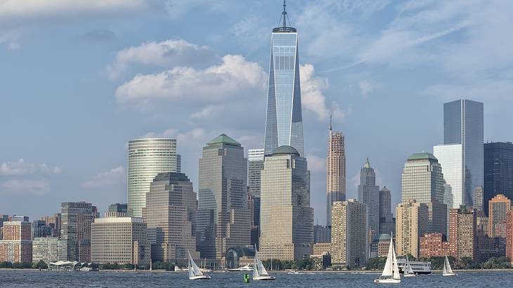 Buildings and skyscrapers along the coast of a river with sailboats on it