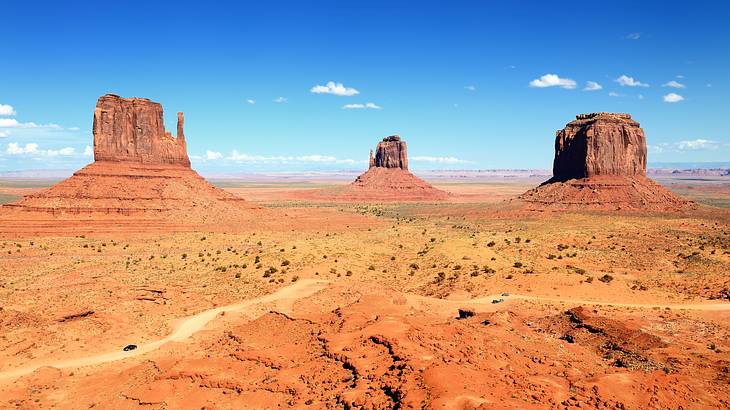 Three red sandstone formations in the middle of a desert