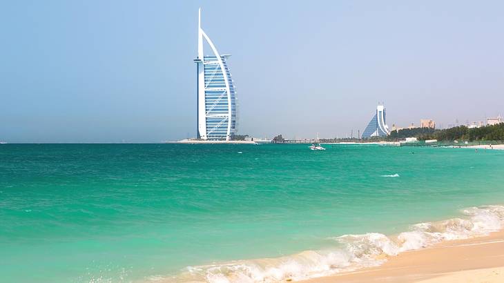 Sand and the turquoise ocean with the modern Burj Al Arab structure on the horizon