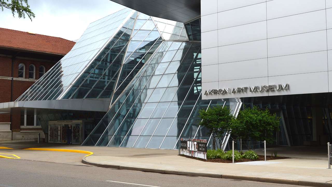 A modern glass building and a sign that says "Akron Art Museum"
