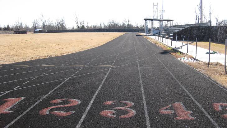 A numbered starting line of a track field with bleachers on its right side