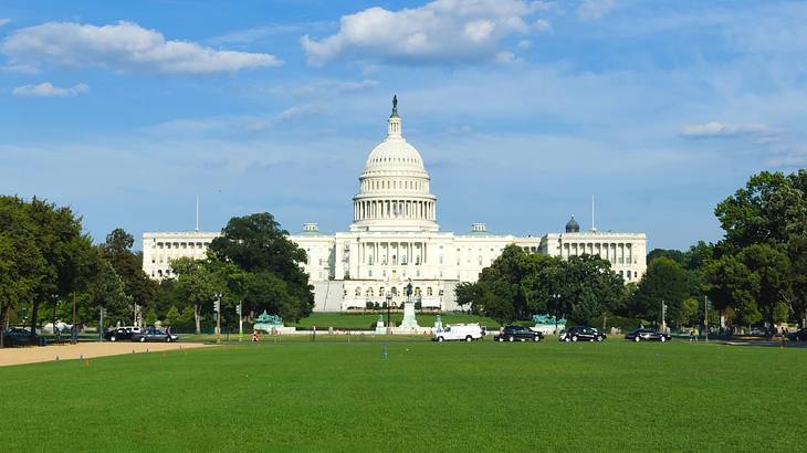 A white stone structure with a domed roof surrounded by grass and trees A white stone structure with a domed roof surrounded by grass and trees