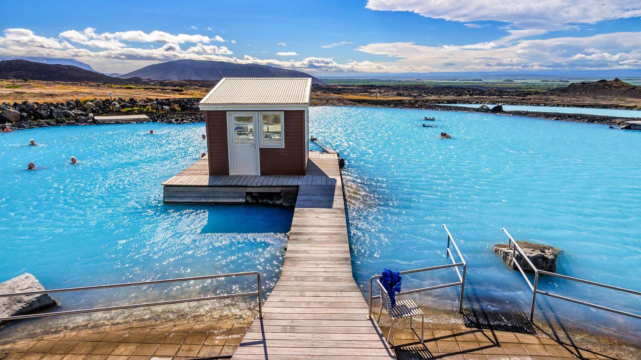 A bright blue lagoon with a wooden walkway and hut in the middle