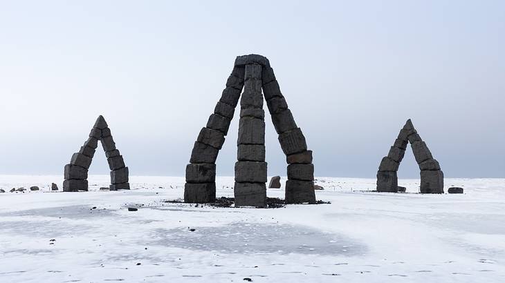 Arch-shaped structures made with black blocks on the snow under an icy sky