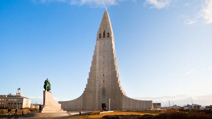 A triangular stone tower structure with a statue in front of it under a blue sky