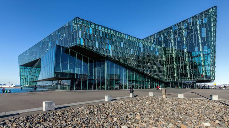 A modern blue glass structure with a path and rocks in front of it