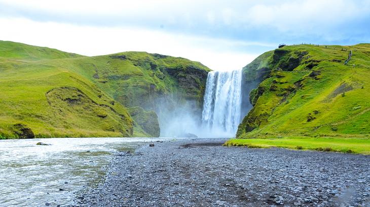 A waterfall flowing through grass-covered hills into a lake