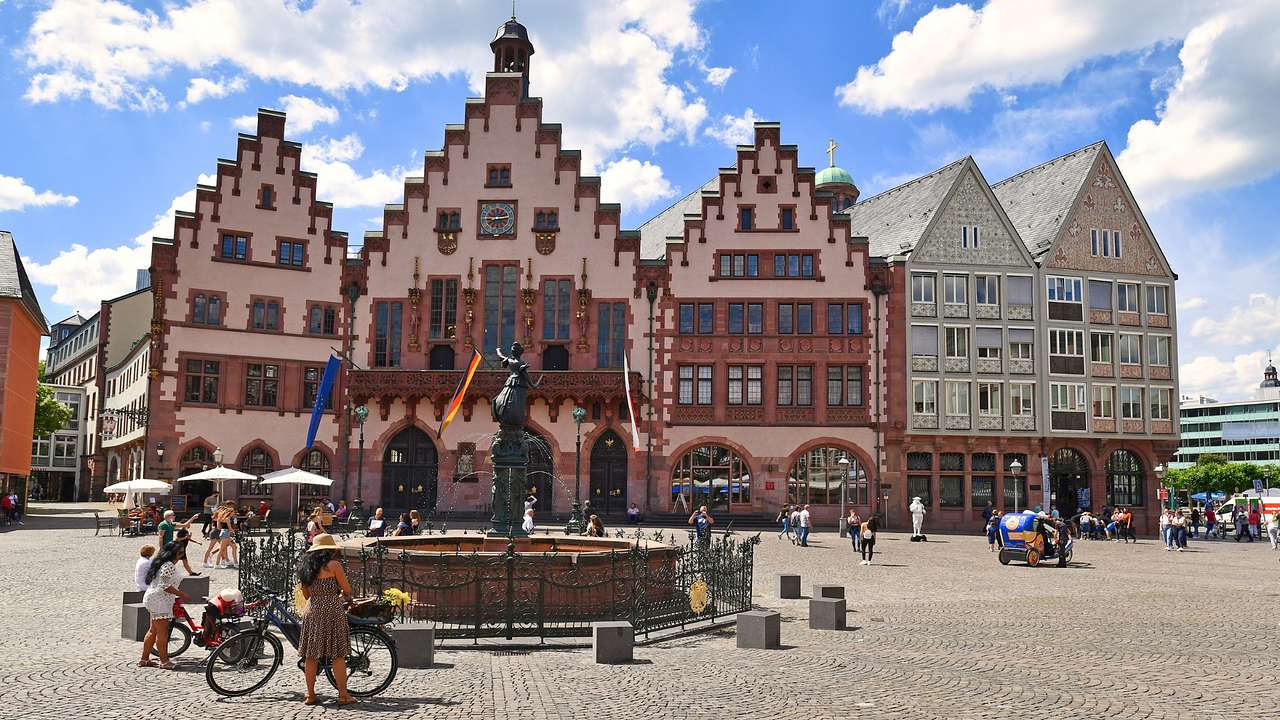 Unique pink and brown buildings next to a square with a small statue in it
