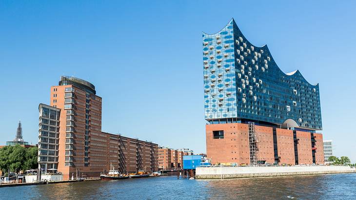 A modern brick and glass building next to a red brick building and a river