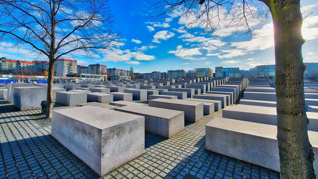 A memorial with concrete, rectangular blocks in rows under a blue sky with clouds