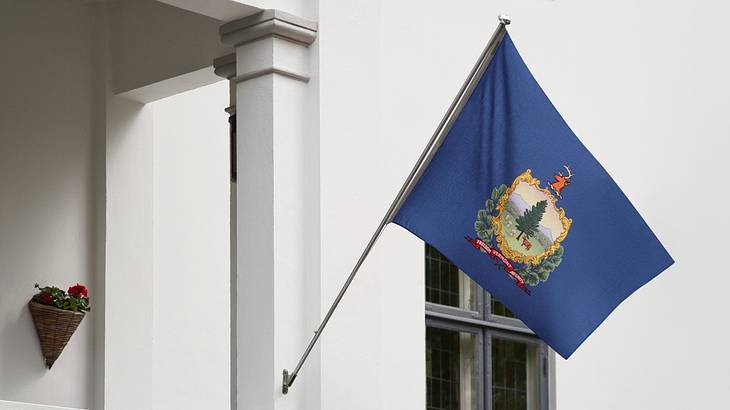 A building with the blue Vermont state flag that has an emblem with a tree on it