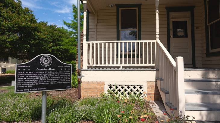 A small house with a porch next to a historical plaque that says "Quakertown House"