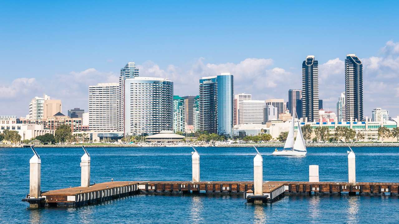 The San Diego skyline next to blue water and a boat dock on a clear day